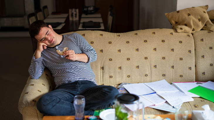 Person on couch surrounded by paperwork