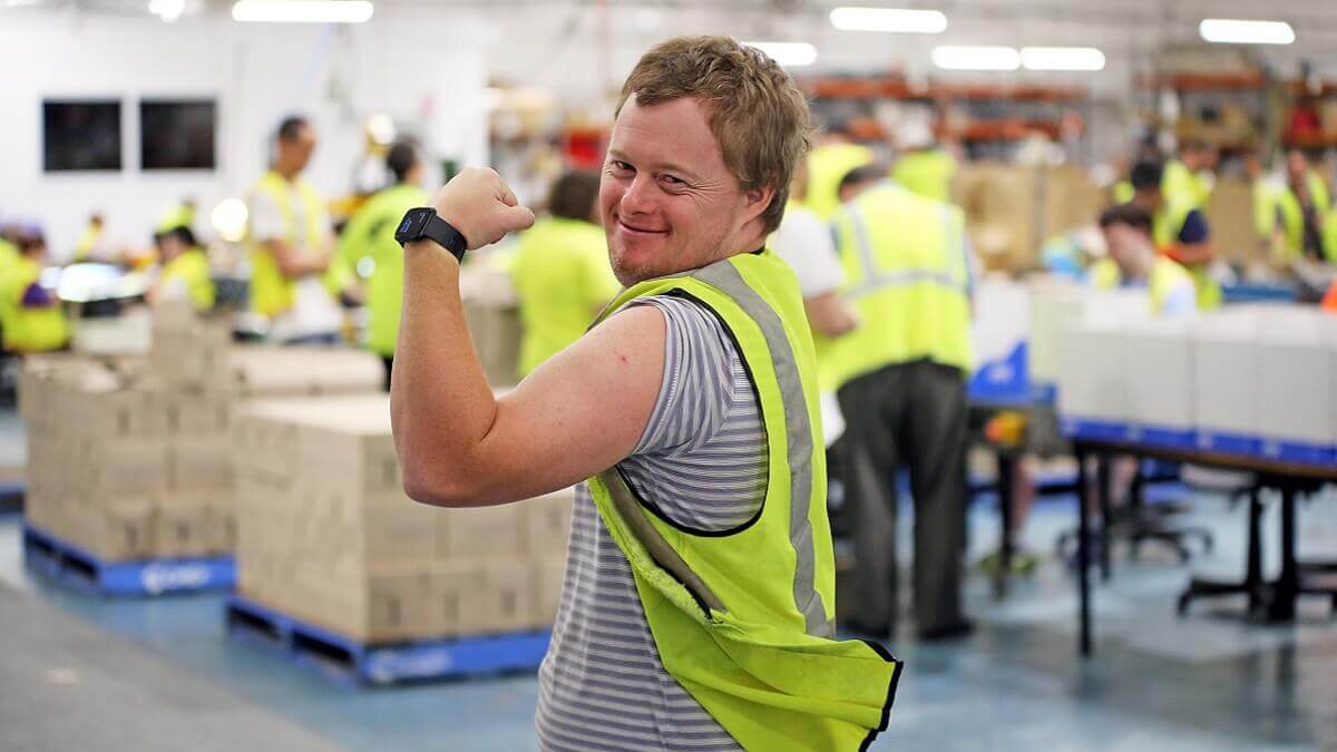 Smiling worker in high visibility clothing in a strong-arm pose