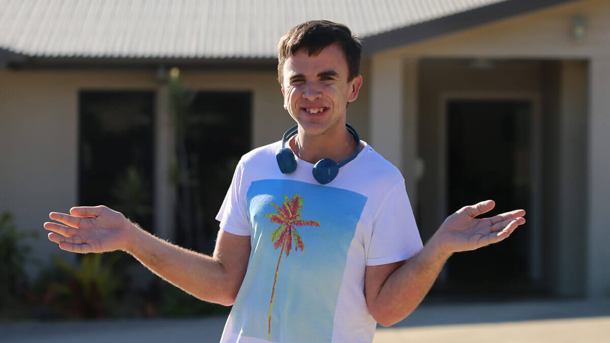 Charlie, smiling wearing headphones in front of his home