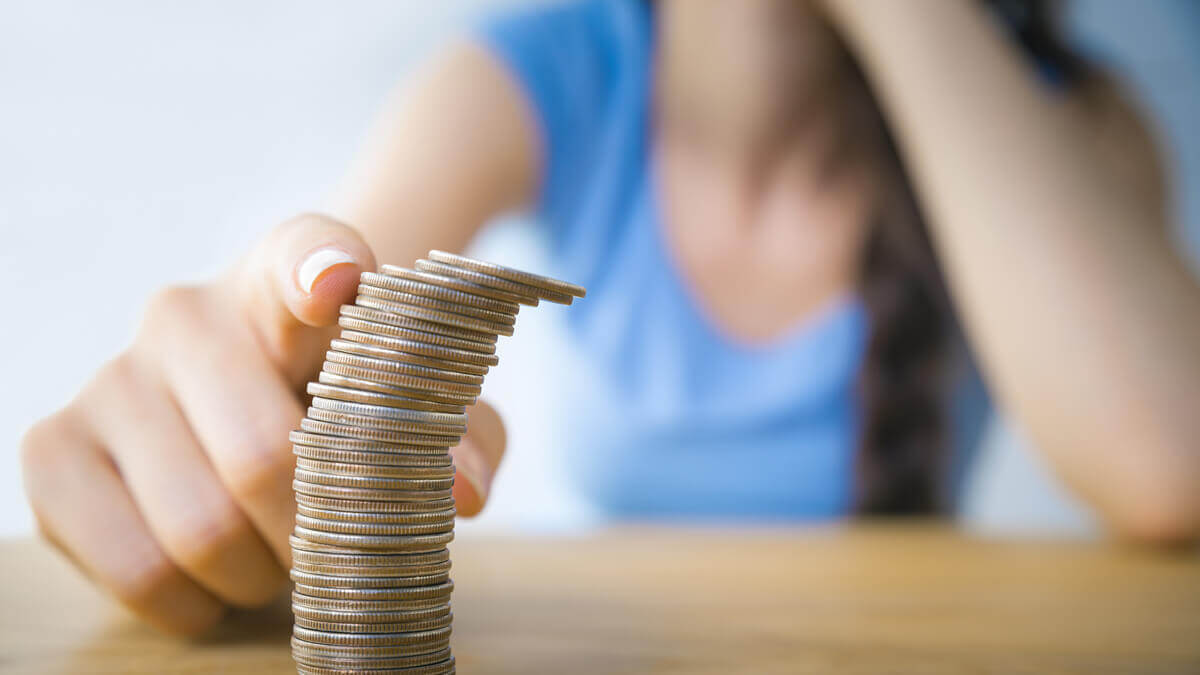 Persons finger tipping over a stack of coins