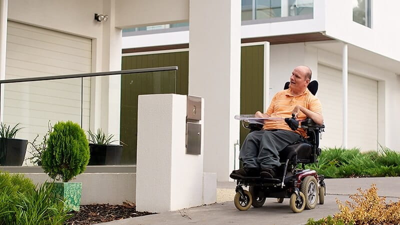 Man outside home operating his own electric wheelchair