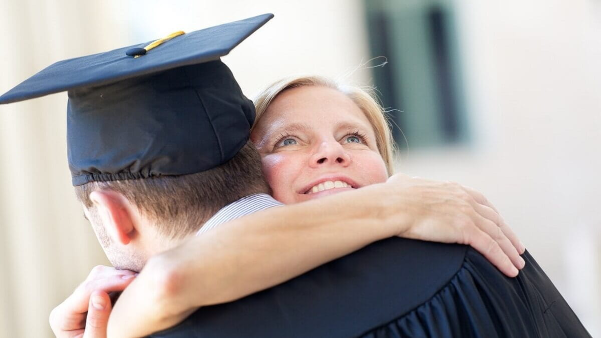 Mother hugging son as he graduates from university