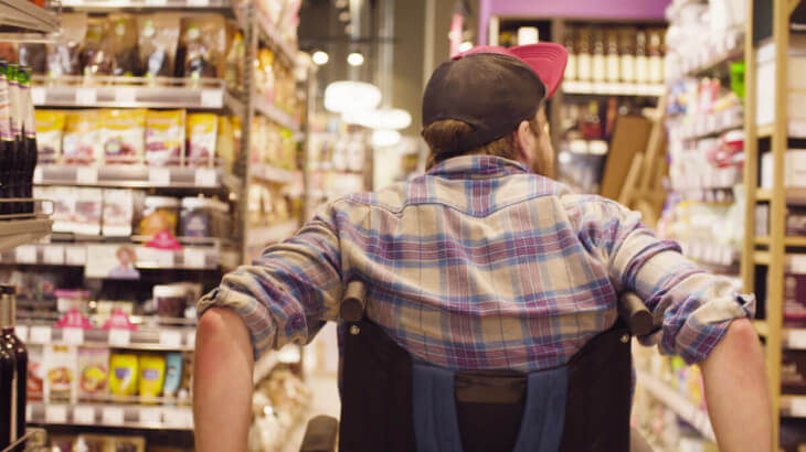 Person wheeling wheelchair through grocery shop