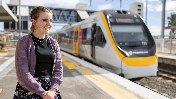 Smiling client standing on train station as train approaches