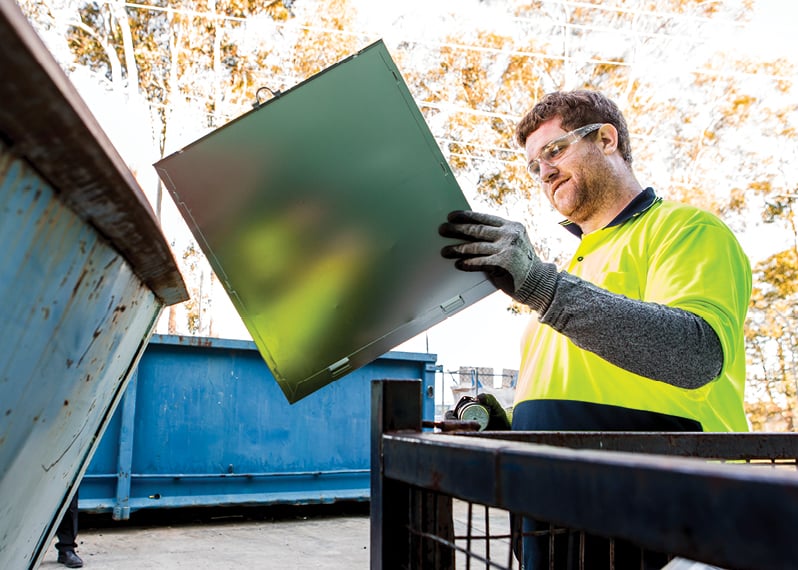 man-holding-ewaste-near-a-large-bin