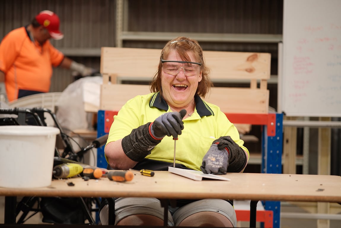 woman-sitting-at-table-smiling-while-working