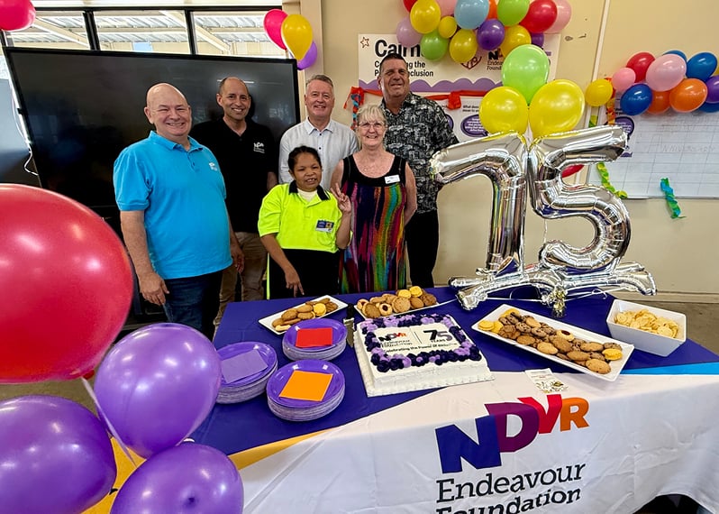 group-posing-in-front-of-table-with-cake-and-balloons