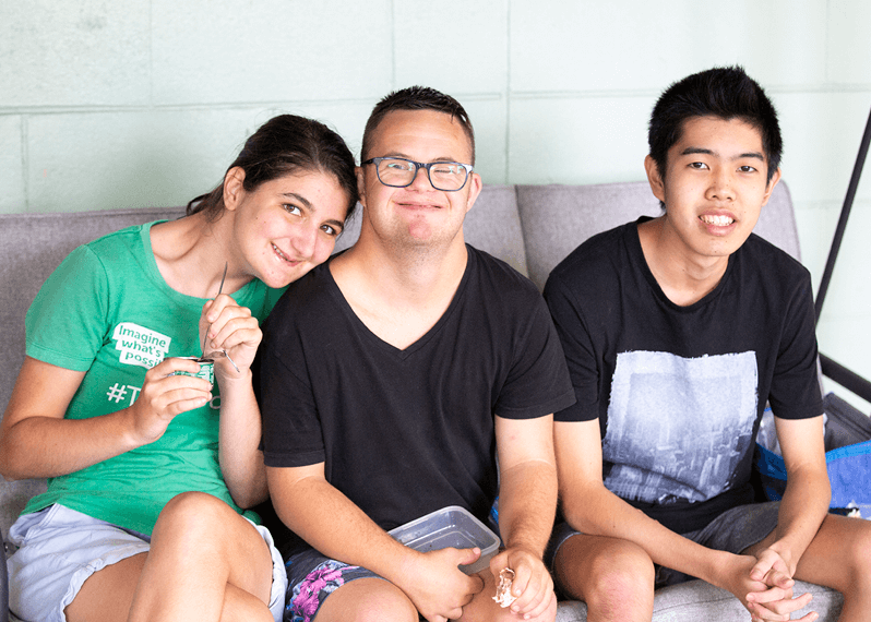 three-people-seated-on-a-couch-smiling