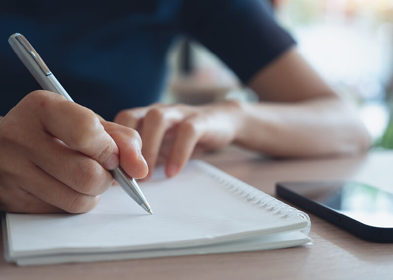 person-holding-pen-near-notepad.jpg
